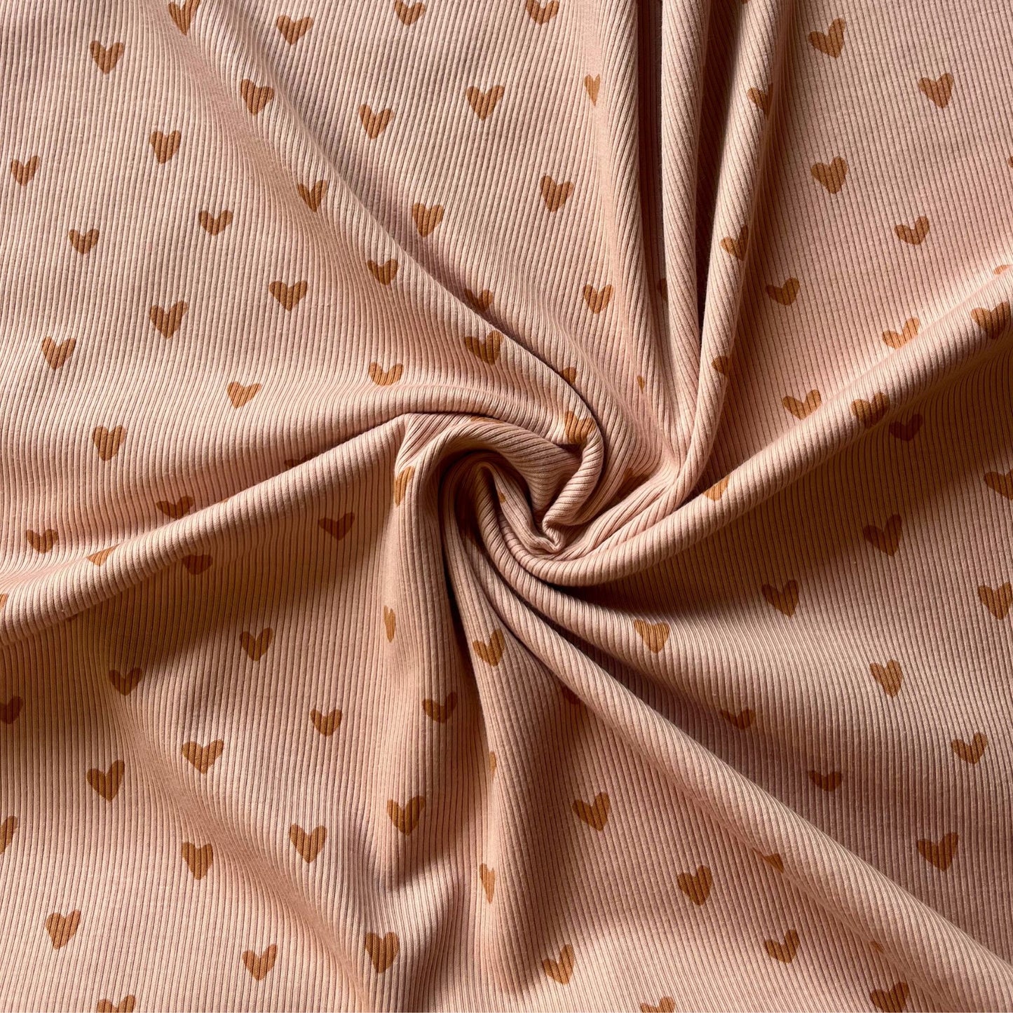 Close-up of fine ribbed jersey with soft Scandinavian-style heart pattern.