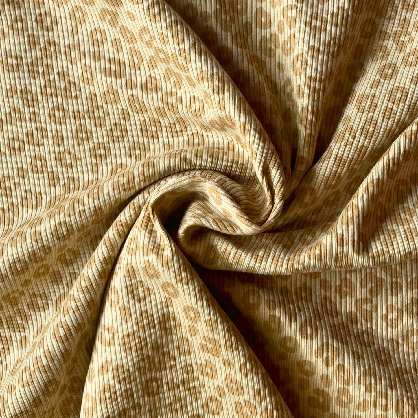 Close-up of fine rib knit texture with playful leopard print for children’s clothing.