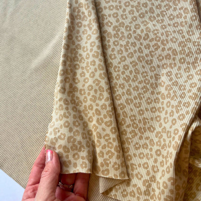 Close-up of a hand holding fabric with a subtle pattern on a neutral background