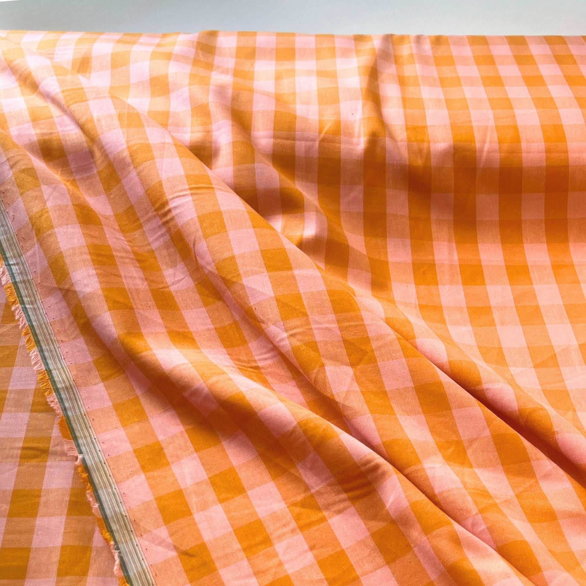 Close-up of orange and salmon yarn dyed gingham check cotton fabric showing crisp 1.75cm check definition and soft woven texture — Oeko-Tex Standard 100 certified, ideal for dressmaking