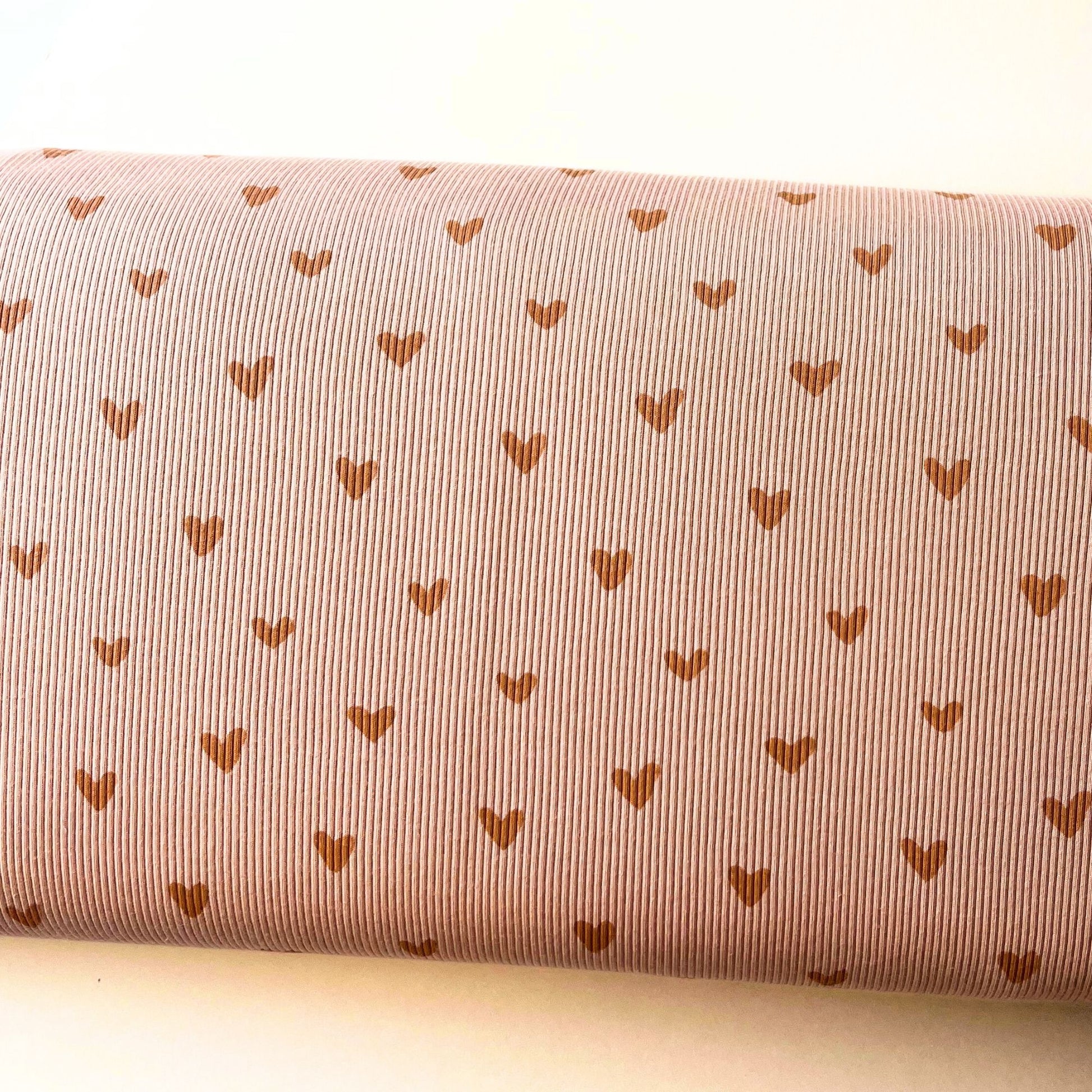 Roll of fabric with small heart patterns on a light neutral background