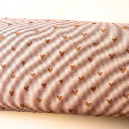 Roll of fabric with small heart patterns on a light neutral background