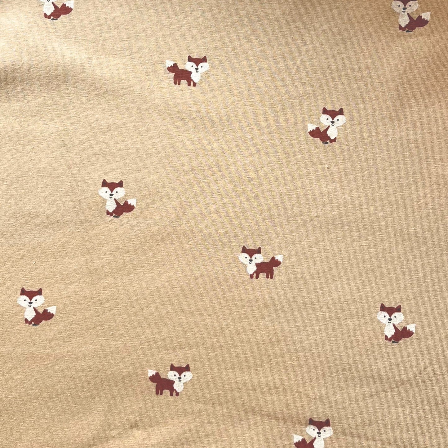 Close-up of friendly illustrated fox faces on breathable cotton stretch fabric.