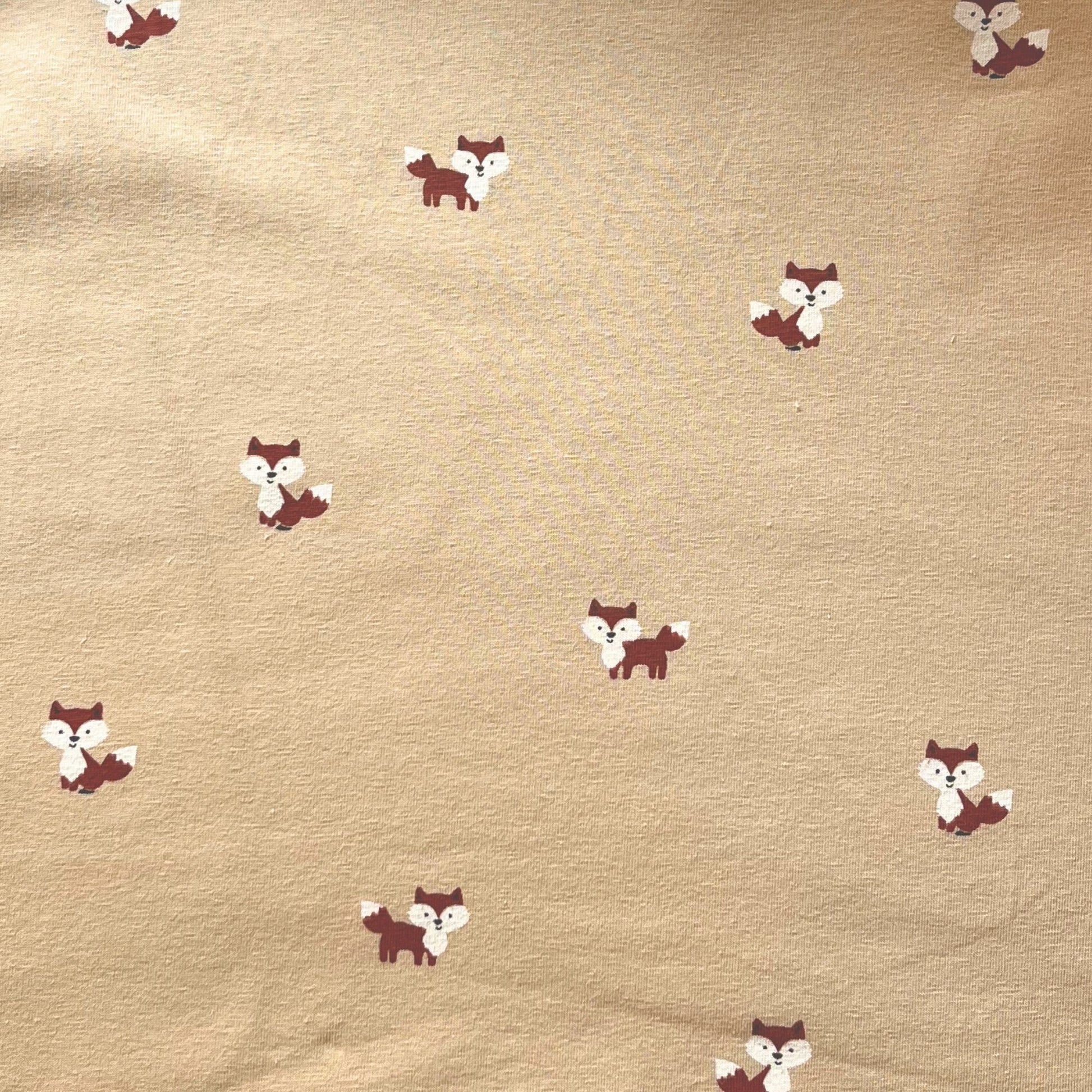 Close-up of friendly illustrated fox faces on breathable cotton stretch fabric.