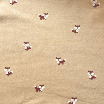 Close-up of friendly illustrated fox faces on breathable cotton stretch fabric.