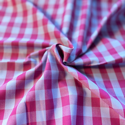 Berry pink and pale blue gingham check yarn dyed woven cotton fabric folded to show crisp check definition — 1.75cm check 145cm wide Oeko-Tex certified lightweight dressmaking fabric for blouses pinafores and summer dresses