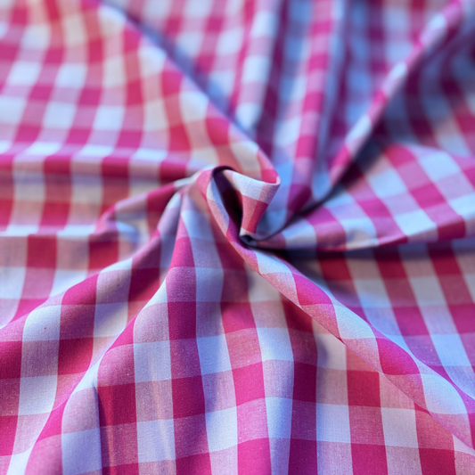 Berry pink and pale blue gingham check yarn dyed woven cotton fabric folded to show crisp check definition — 1.75cm check 145cm wide Oeko-Tex certified lightweight dressmaking fabric for blouses pinafores and summer dresses
