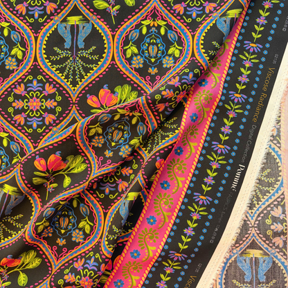 Black bohemian tropical digital viscose woven fabric folded to show fluid drape and vivid leopard palm print in pink purple blue green and orange — 142cm wide lightweight dressmaking fabric for wrap dresses skirts and kimono jackets