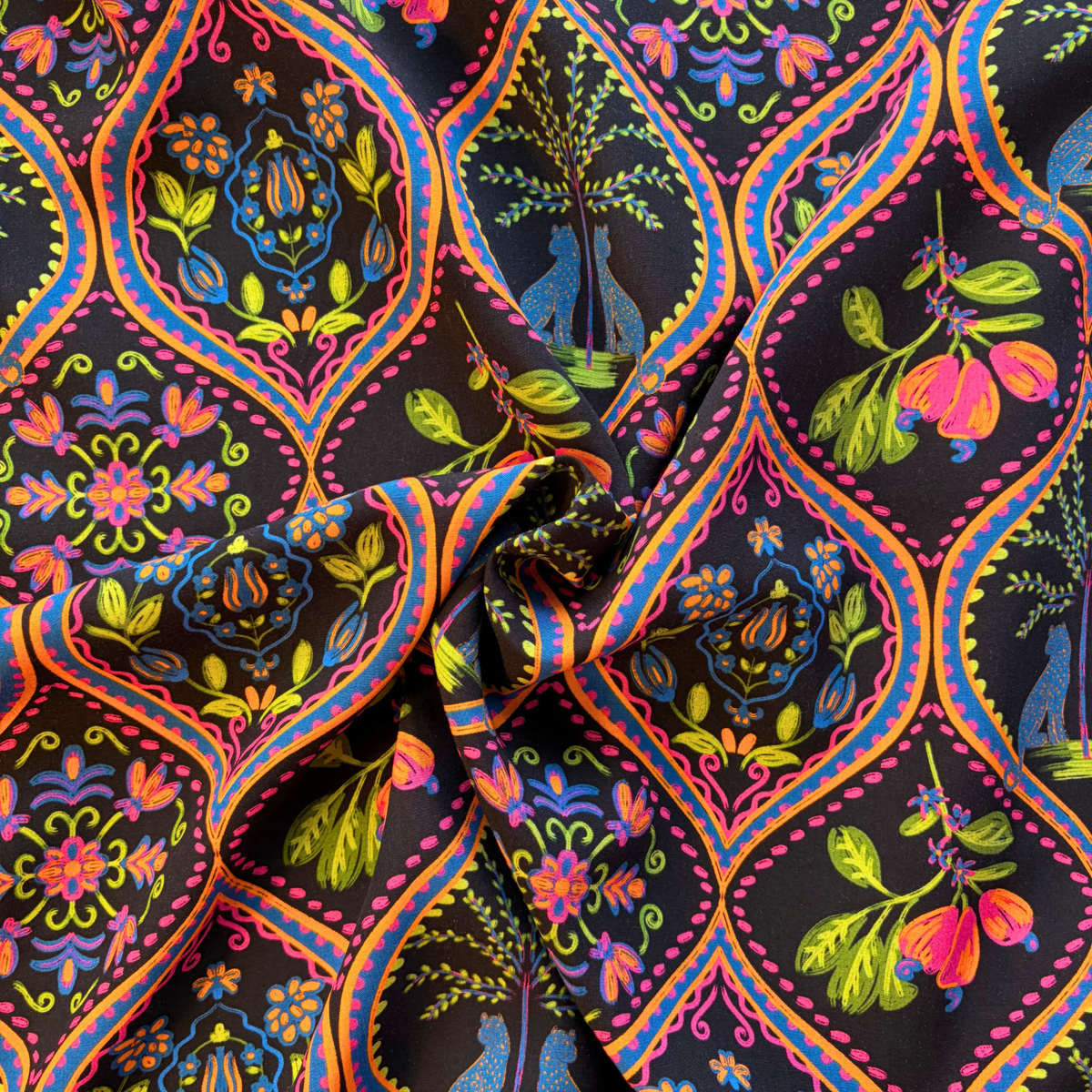 Black tropical bohemian digital print viscose fabric flat lay showing 110gsm fluid drape and 142cm width — leopard and palm motifs in pink purple blue and orange perfect for handmade wrap dresses and wide-leg trousers
