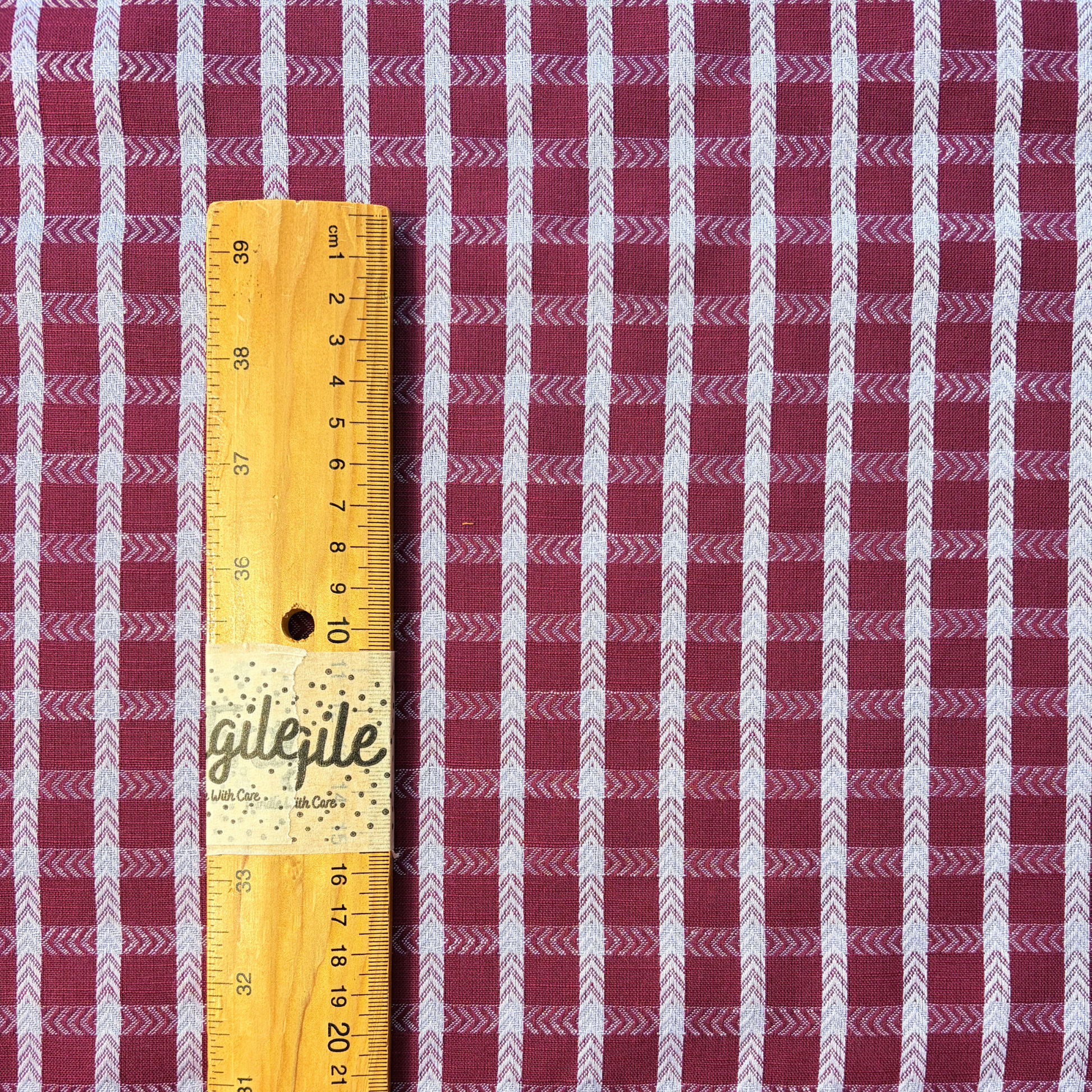 Burgundy lilac dobby check woven cotton fabric folded to show raised 1.8cm grid texture and soft construction — 145cm wide lightweight dressmaking fabric for handmade blouses dresses and skirts