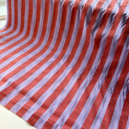 Burnt orange and lavender vertical stripe yarn dyed cotton fabric folded to show woven construction — 2.2cm stripe 145cm wide Oeko-Tex certified lightweight dressmaking fabric for blouses pinafores and summer dresses