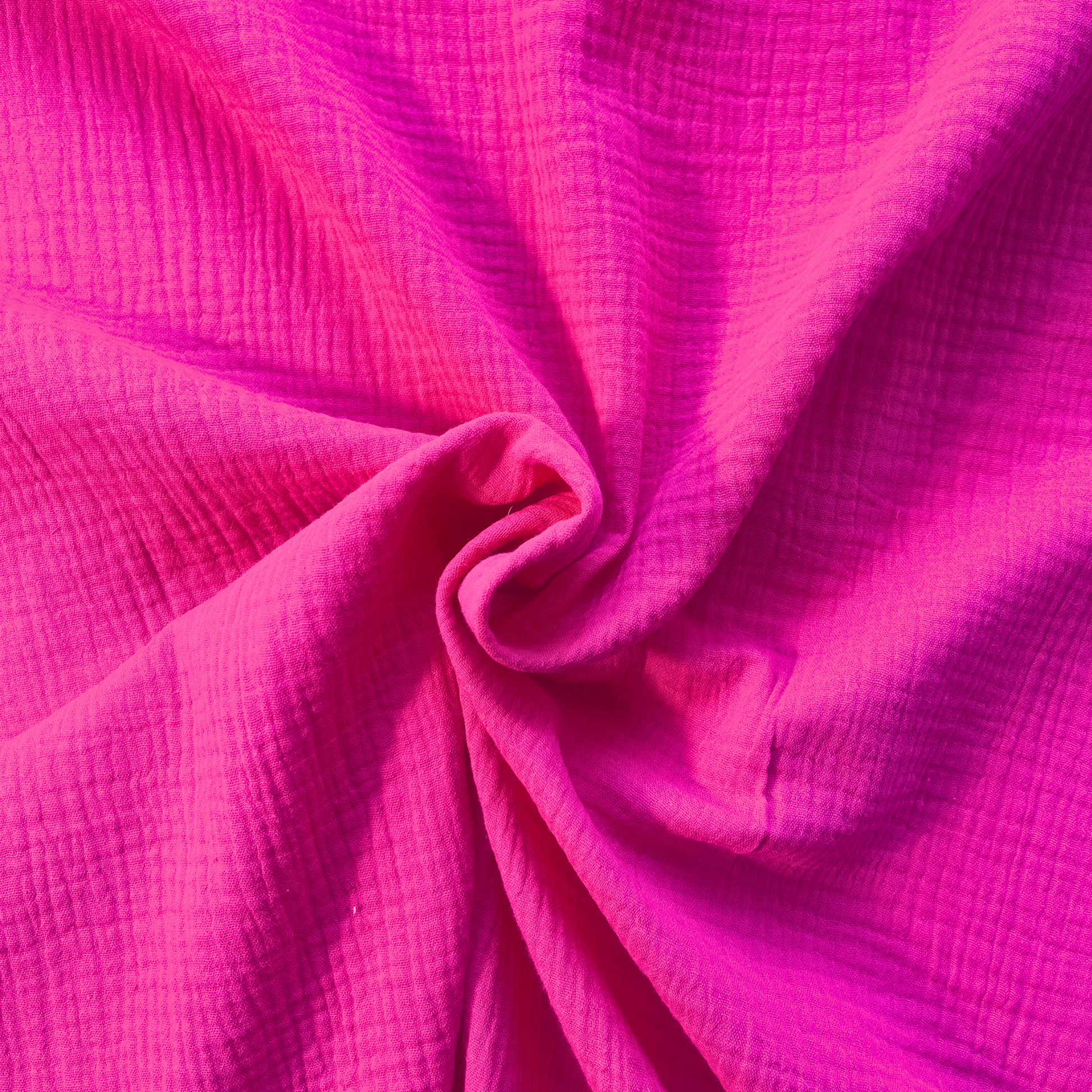 Bright cerise pink plain double gauze folded to show soft two-layer GOTS certified organic cotton construction — featherlight breathable fabric ideal for handmade baby muslins, children's dresses and statement adult garments