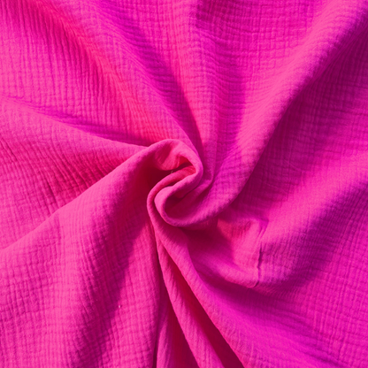 Bright cerise pink plain double gauze folded to show soft two-layer GOTS certified organic cotton construction — featherlight breathable fabric ideal for handmade baby muslins, children's dresses and statement adult garments