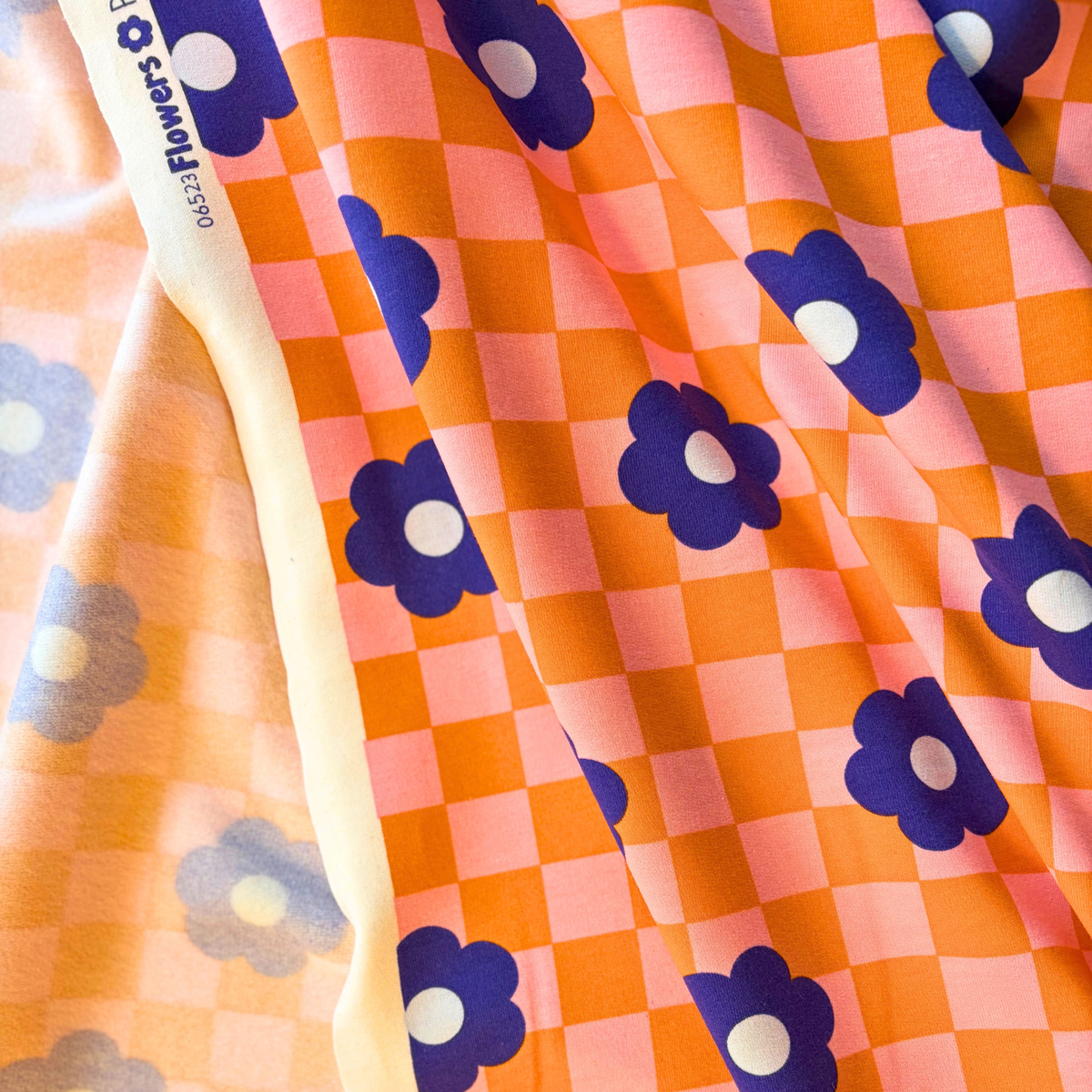 Orange and pink checkerboard sweatshirting fabric with blue retro floral print 148cm wide — 225gsm 95% cotton 5% elastane brushed stretch knit Oeko-Tex certified for handmade sweatshirts and children's clothing