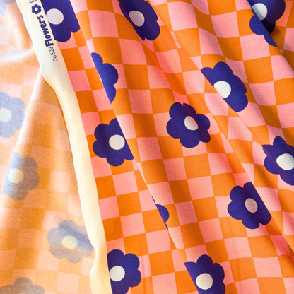 Orange and pink checkerboard sweatshirting fabric with blue retro floral print 148cm wide — 225gsm 95% cotton 5% elastane brushed stretch knit Oeko-Tex certified for handmade sweatshirts and children's clothing
