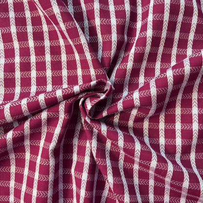 Close-up of burgundy and lilac dobby check woven cotton fabric showing raised 1.8cm grid texture and soft woven construction — 135gsm slow fashion dressmaking fabric UK