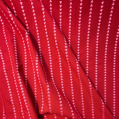 Close-up of burnt red and pink yarn dyed dobby triangle stripe woven cotton fabric showing raised vertical mini triangle texture — reversible cut direction 135gsm slow fashion dressmaking fabric UK