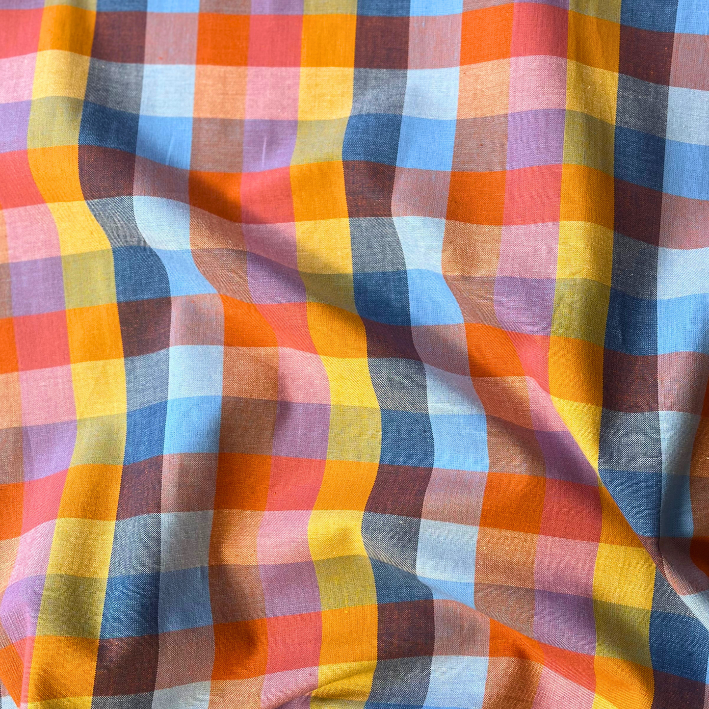 Close-up of Fableism Fine and Dandy Cornucopia Happy Checkers woven cotton fabric showing 3cm multicolour gingham check in yellow orange blue and pink — lightweight 135gsm slow fashion dressmaking fabric UK