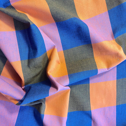 Close-up of Fableism Fine and Dandy Happy Checkers woven cotton fabric showing bold 7.5cm multicolour check in cobalt blue orange khaki and lilac — lightweight 135gsm dressmaking fabric ideal for slow fashion sewing