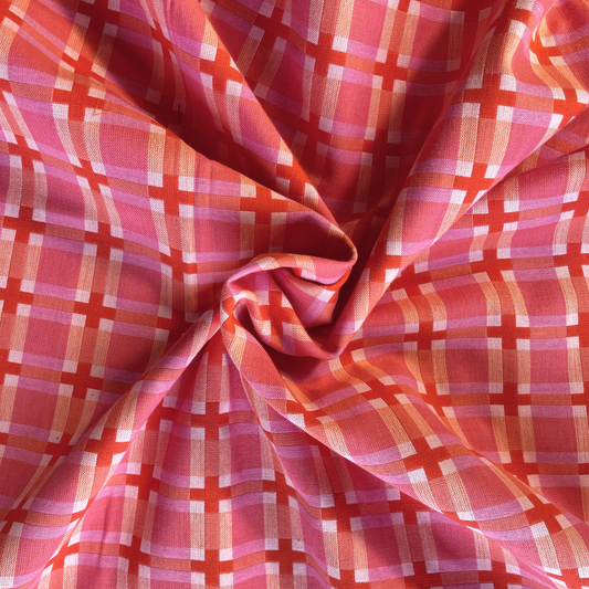 Close-up of Fableism Fine and Dandy Summer Decked Out woven cotton fabric showing warm pink base with cream and burnt orange 3.5cm grid check — heavyweight 240gsm slow fashion dressmaking fabric UK
