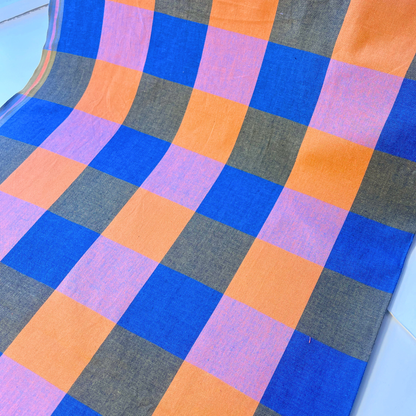Flat lay of Fableism Happy Checkers Suit 3 multicolour giant check cotton fabric draped to show 135gsm natural drape and 110cm width — cobalt blue orange khaki brown and pinky lilac woven check perfect for handmade dresses and trousers