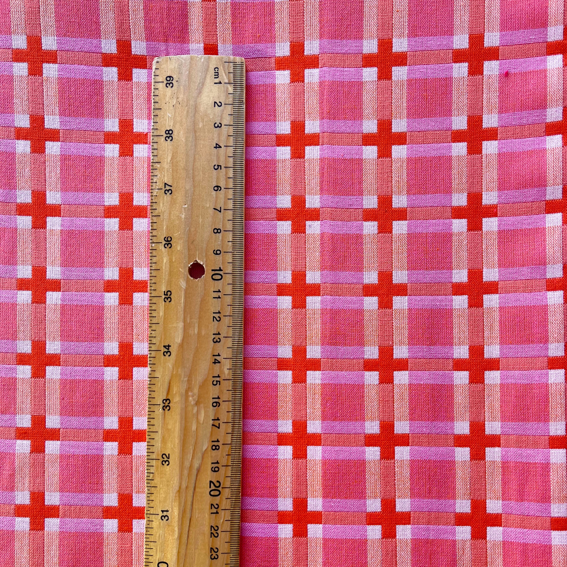 Fableism Summer Decked Out warm pink grid check woven cotton fabric folded to show heavyweight 240gsm construction — 110cm wide dressmaking fabric in pink cream and burnt orange for handmade dresses trousers and autumn layers