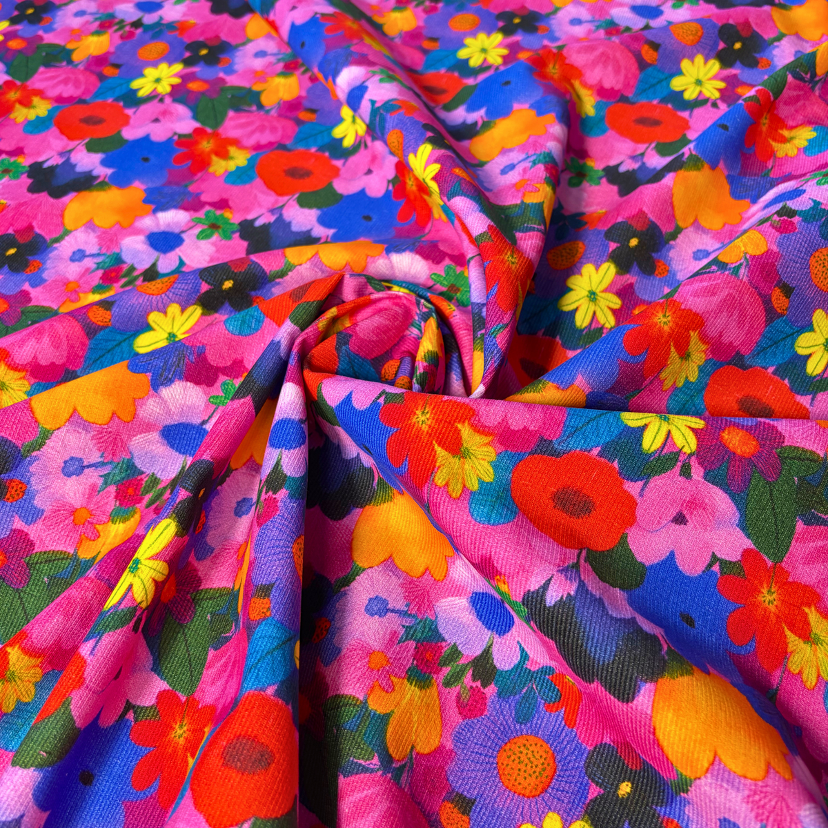 Close-up of bright floral cotton needlecord showing densely packed flower heads with no background colour, soft corduroy texture slow fashion dressmaking fabric UK