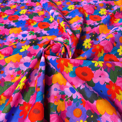 Close-up of bright floral cotton needlecord showing densely packed flower heads with no background colour, soft corduroy texture slow fashion dressmaking fabric UK