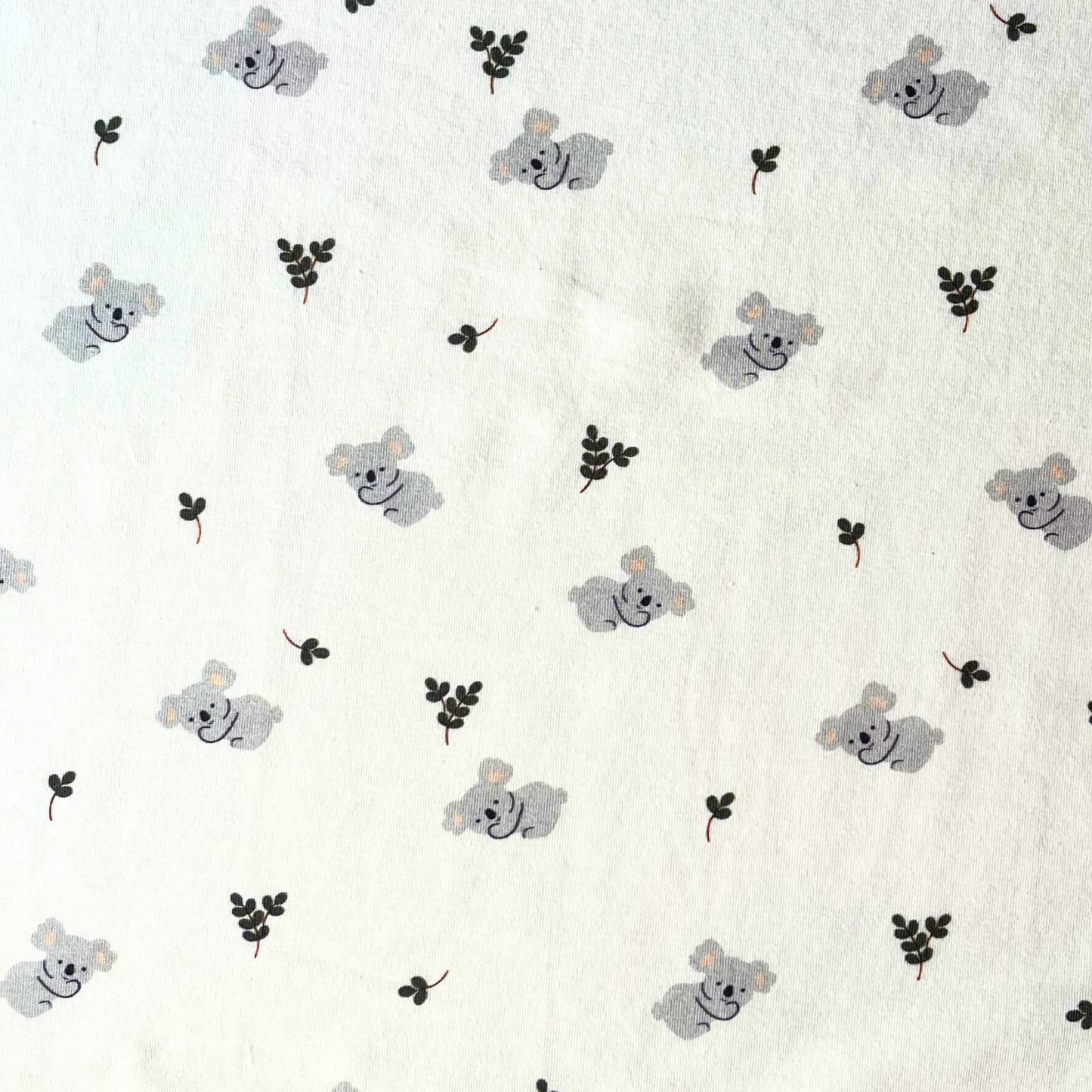 Pattern of koala bears and leaves on a white jersey fabric