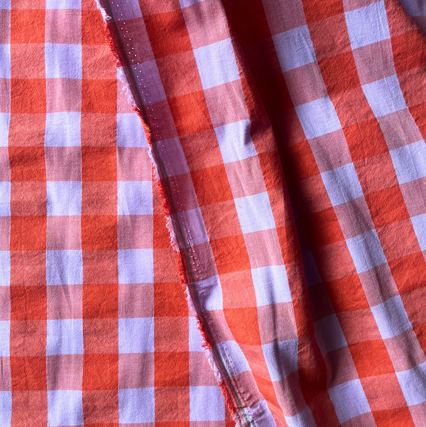 Flat lay of terracotta orange and lilac gingham cotton fabric draped to show 135gsm weight and natural drape — 3cm yarn dyed check fabric perfect for handmade women's statement dresses and autumn blouses