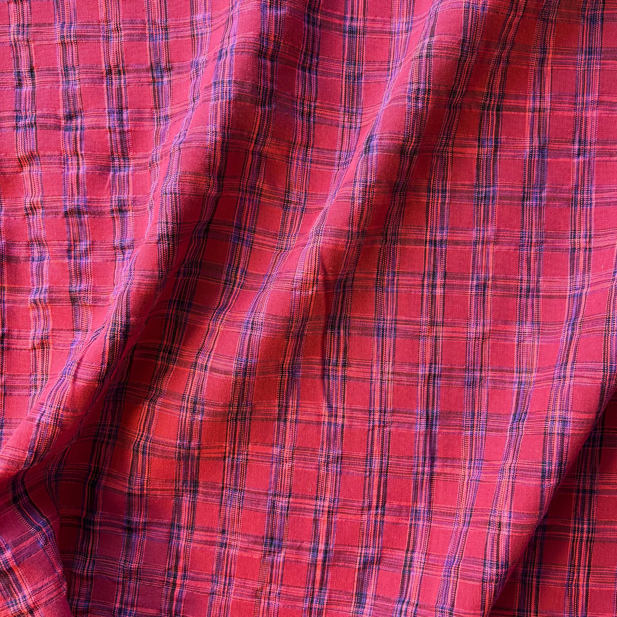 Close-up of berry neon pink and cobalt blue yarn dyed woven check fabric showing rippling 2cm check detail — 100gsm lightweight Oeko-Tex Standard 100 certified slow fashion dressmaking fabric UK