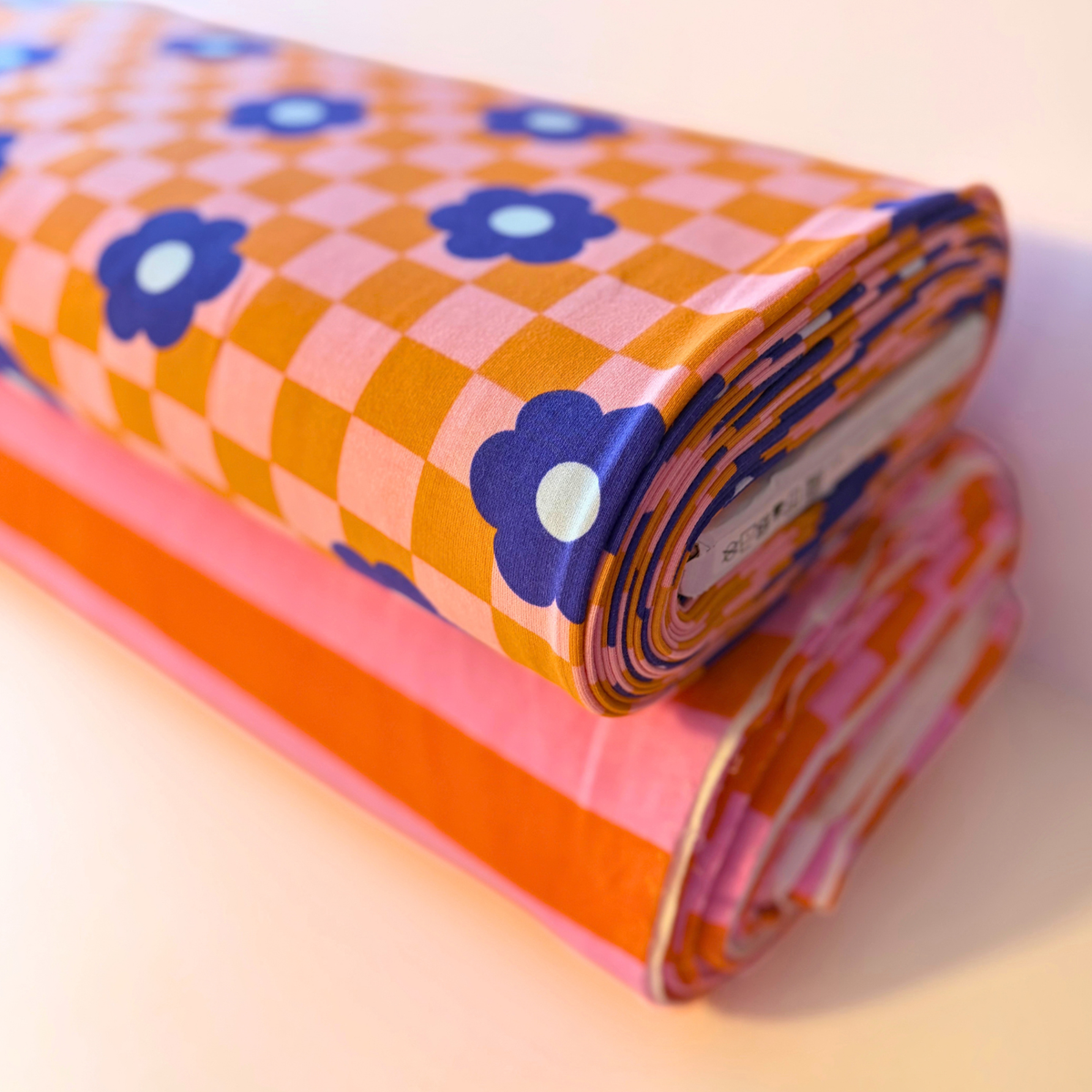 Orange pink checkerboard blue retro floral sweatshirting folded to show soft brushed interior — 148cm wide 225gsm cotton elastane Oeko-Tex certified stretch fabric for handmade sweatshirts and children's clothing
