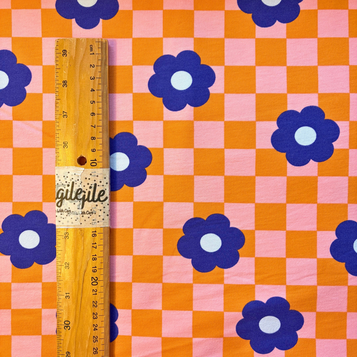 Orange pink checkerboard floral sweatshirting flat lay showing 225gsm weight and 148cm width — retro blue flower print stretch fabric perfect for handmade sweatshirts hoodies and children's tops