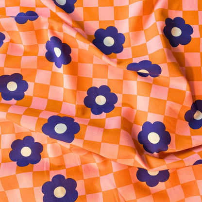 Close-up of orange pink checkerboard sweatshirting with medium blue retro bloom print showing soft brushed interior — 225gsm cotton elastane Oeko-Tex Standard 100 certified stretch fabric UK