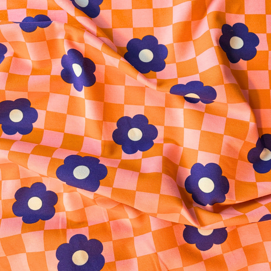 Close-up of orange pink checkerboard sweatshirting with medium blue retro bloom print showing soft brushed interior — 225gsm cotton elastane Oeko-Tex Standard 100 certified stretch fabric UK