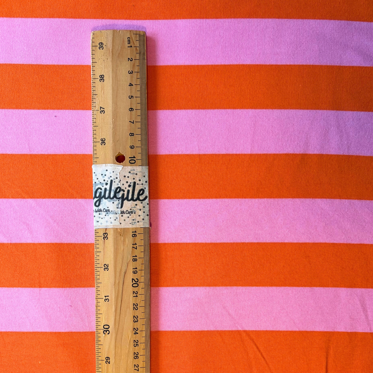 Close-up of orange and pink stripe brushed sweatshirting fabric showing 3.5cm horizontal stripe and soft brushed interior — 225gsm cotton elastane Oeko-Tex Standard 100 certified stretch fabric UK