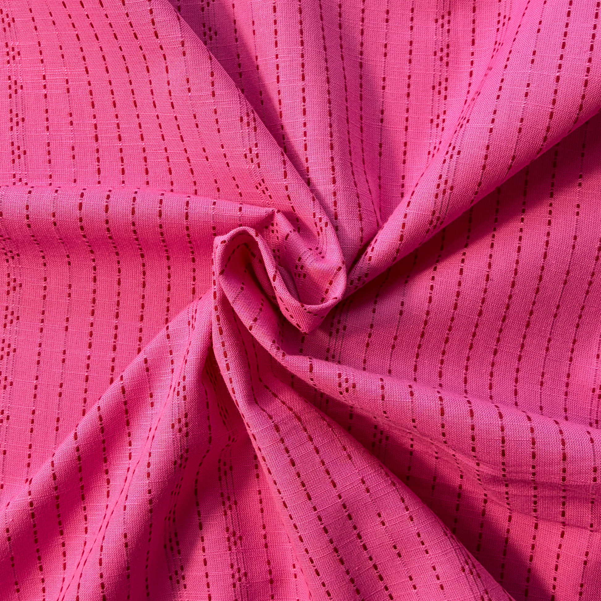 Pink and lilac dobby stripe yarn dyed woven cotton fabric folded to show raised vertical dot and dash texture — 145cm wide lightweight dressmaking fabric for handmade blouses shirts dresses and skirts