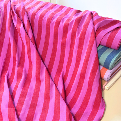 Red cerise pink 2.2cm yarn dyed stripe cotton fabric draped to show natural drape and 145cm width — coordinates with matching gingham for handmade children's pinafores summer dresses and blouses