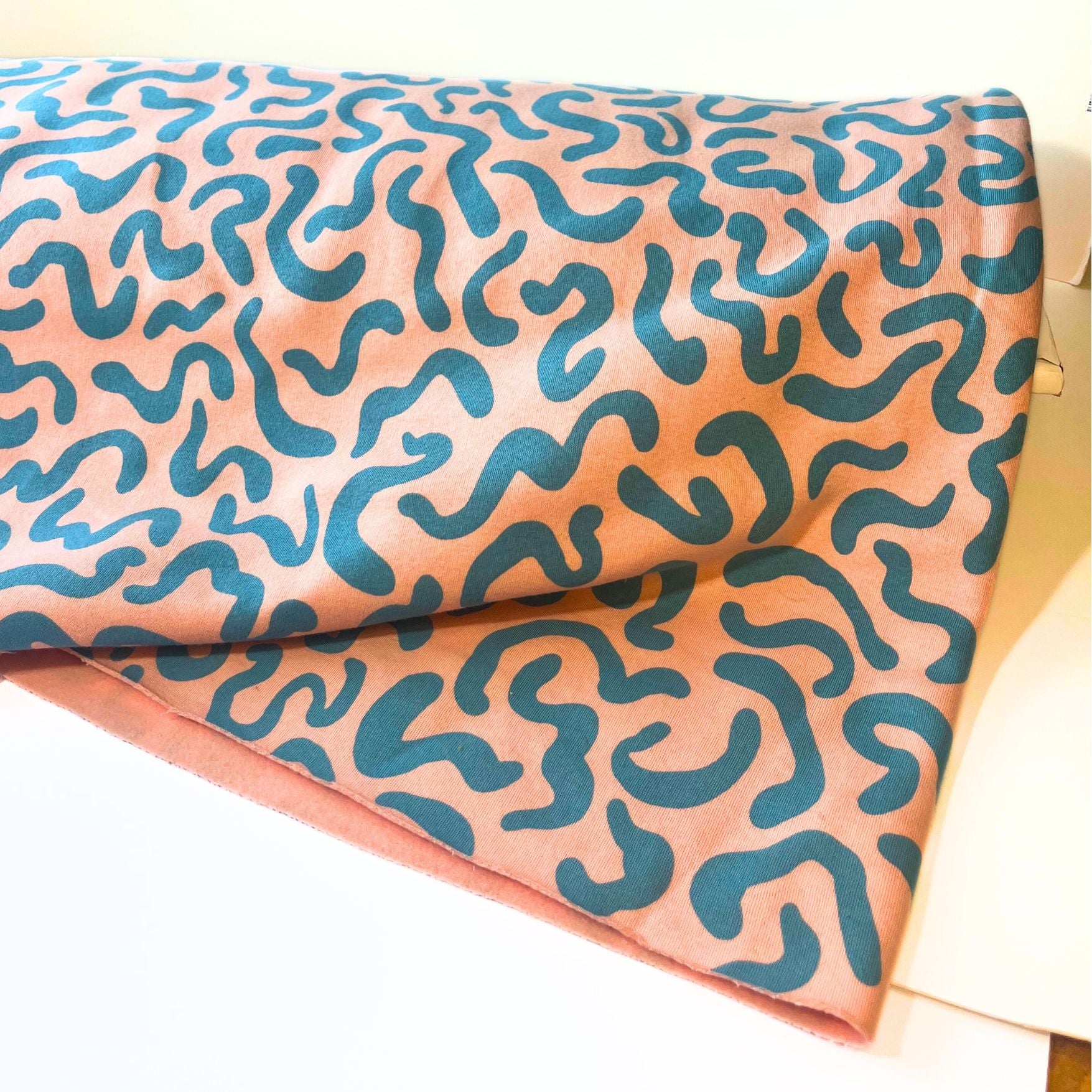 sweatshirt Fabric with teal wavy pattern on a peach background