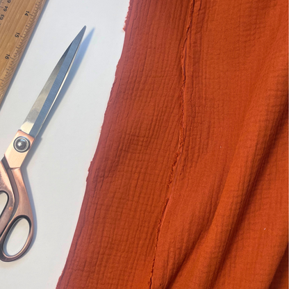 Close-up of terracotta plain double gauze fabric showing soft two-layer organic cotton construction — GOTS certified 125gsm woven ideal for handmade children's dresses, baby swaddles and adult blouses