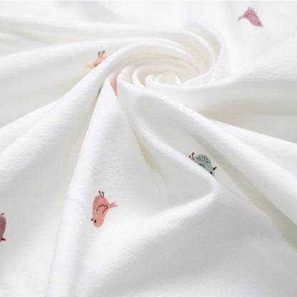 Flat lay of white miniature birds jersey fabric draped to show 200gsm weight and stretch — delicate nature-inspired bird print in soft muted tones perfect for handmade baby gifts and children's slow fashion sewing