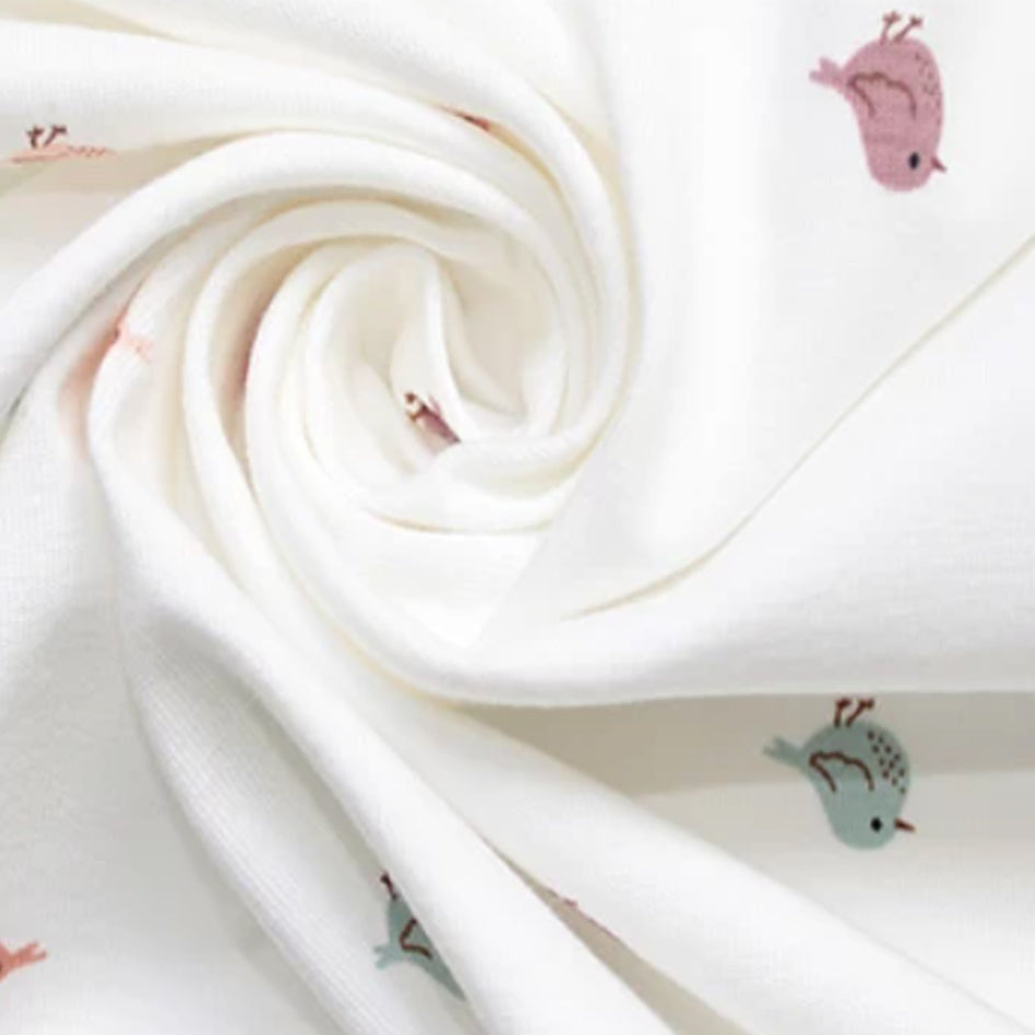 White cotton stretch jersey with scattered miniature bird print in soft rose, putty and teal — 95% cotton 5% elastane knit, gentle on sensitive skin and perfect for handmade babygrows, rompers and children's tops
