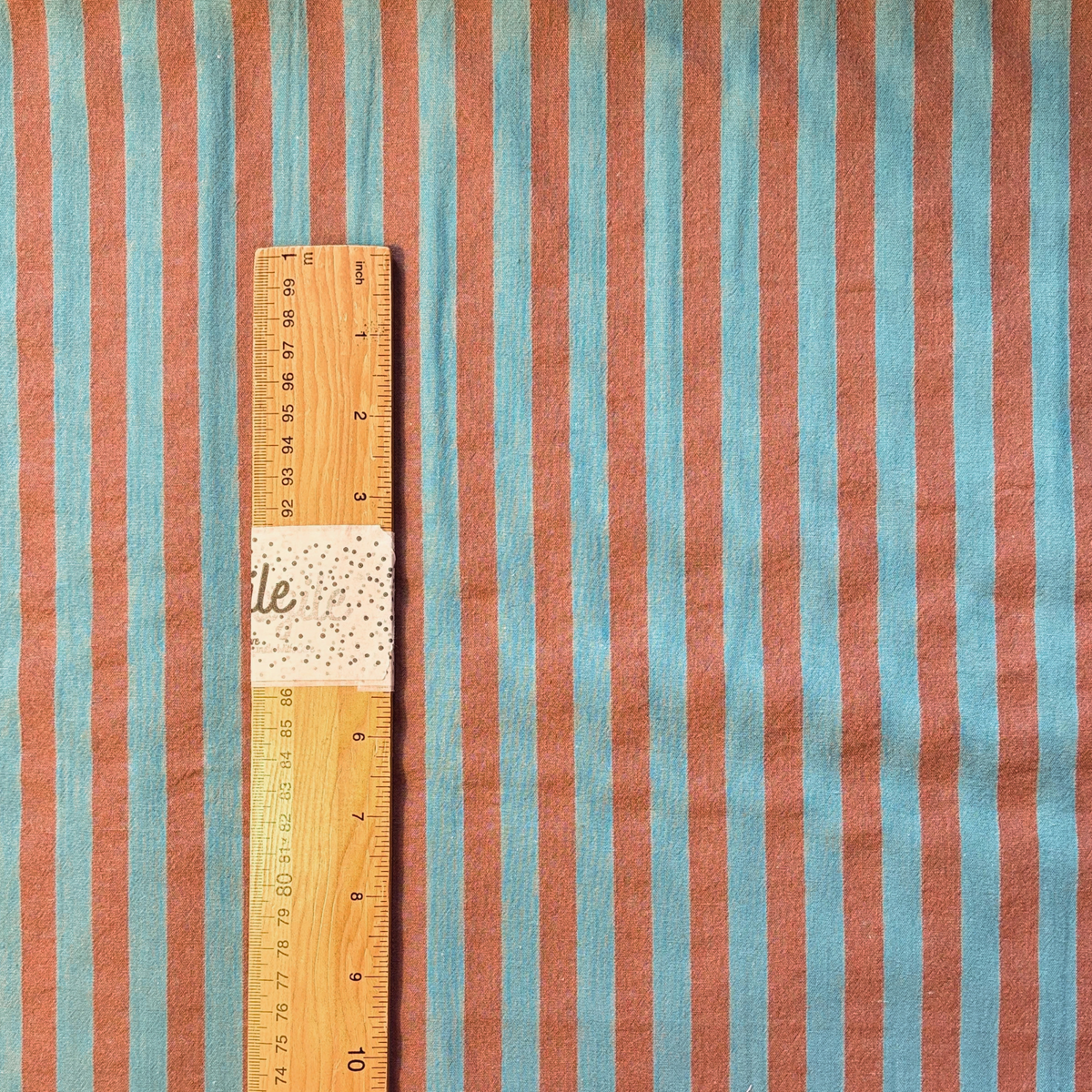 Washed brown and teal yarn dyed stripe woven cotton fabric folded to show soft stripe definition — 1.25cm stripe 145cm wide Oeko-Tex certified lightweight dressmaking fabric for blouses shirts and summer dresses