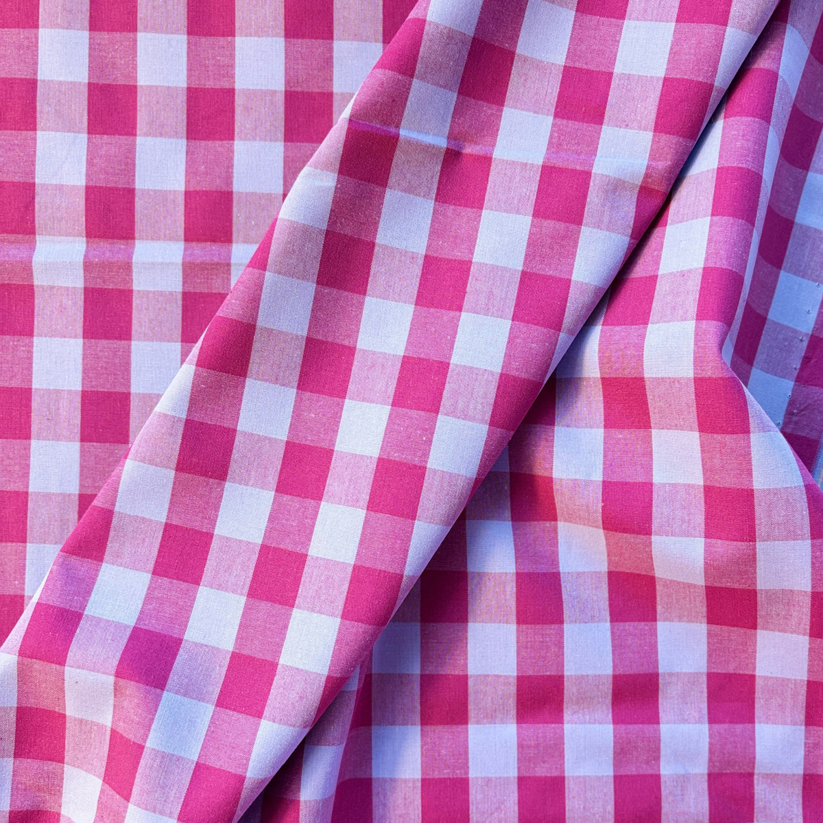 Close-up of berry pink and pale blue yarn dyed gingham check woven cotton fabric showing crisp 1.75cm check definition — 115gsm Oeko-Tex Standard 100 certified slow fashion dressmaking fabric UK