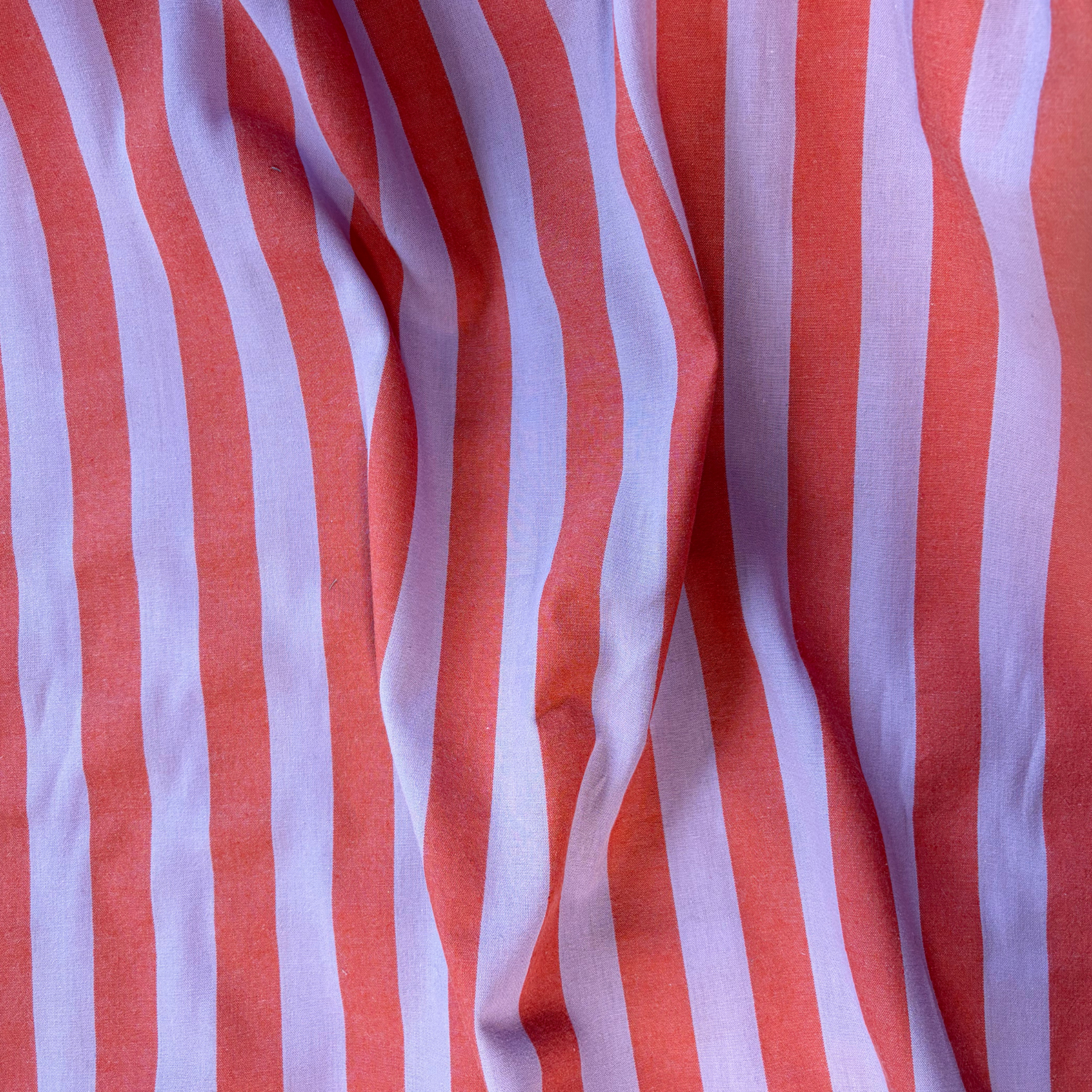 Close-up of burnt orange and lavender yarn dyed vertical stripe cotton fabric — crisp 2.2cm stripe definition 135gsm woven Oeko-Tex Standard 100 certified slow fashion dressmaking fabric UK
