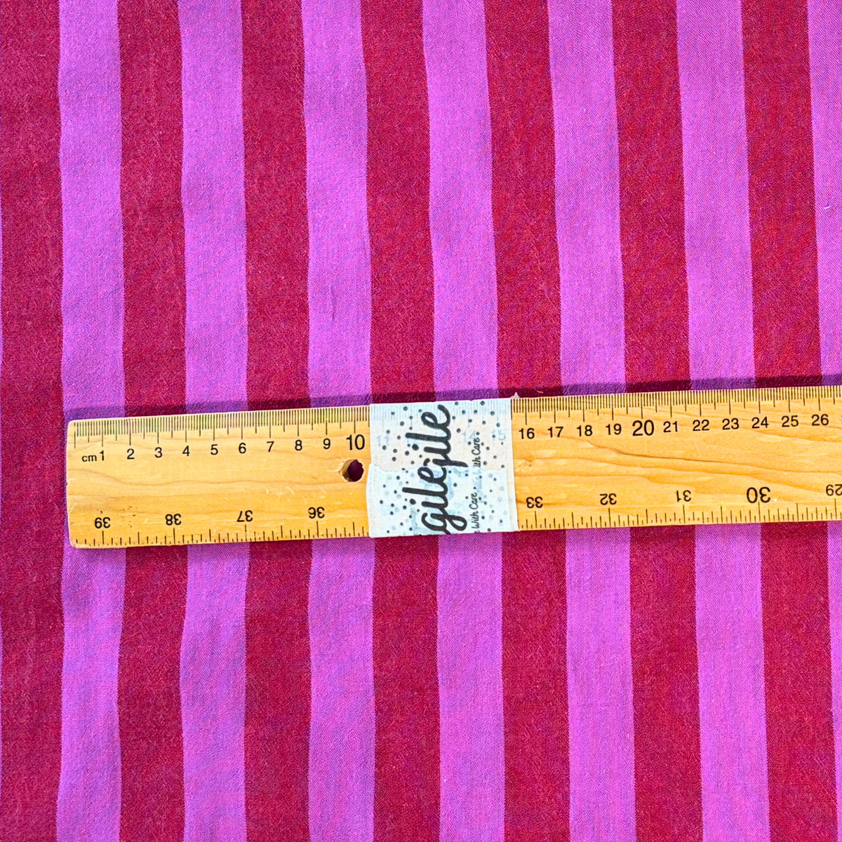 Close-up of red and cerise pink yarn dyed vertical stripe cotton fabric — crisp 2.2cm stripe definition 135gsm woven Oeko-Tex Standard 100 certified slow fashion dressmaking fabric UK